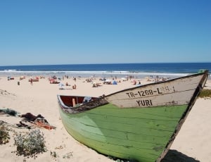 green and white wooden boat in the sand pictuure during day time thumbnail