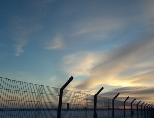 silhouette of fence beside sea during sunset thumbnail