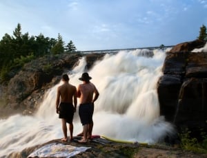 3 person standing near waterfalls during daytime thumbnail