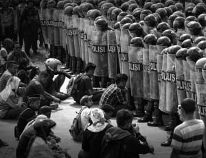 group of people sitting in front of police in grayscale photography thumbnail