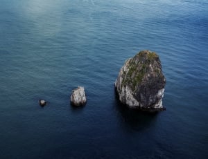 grey rock formation on large body of water thumbnail