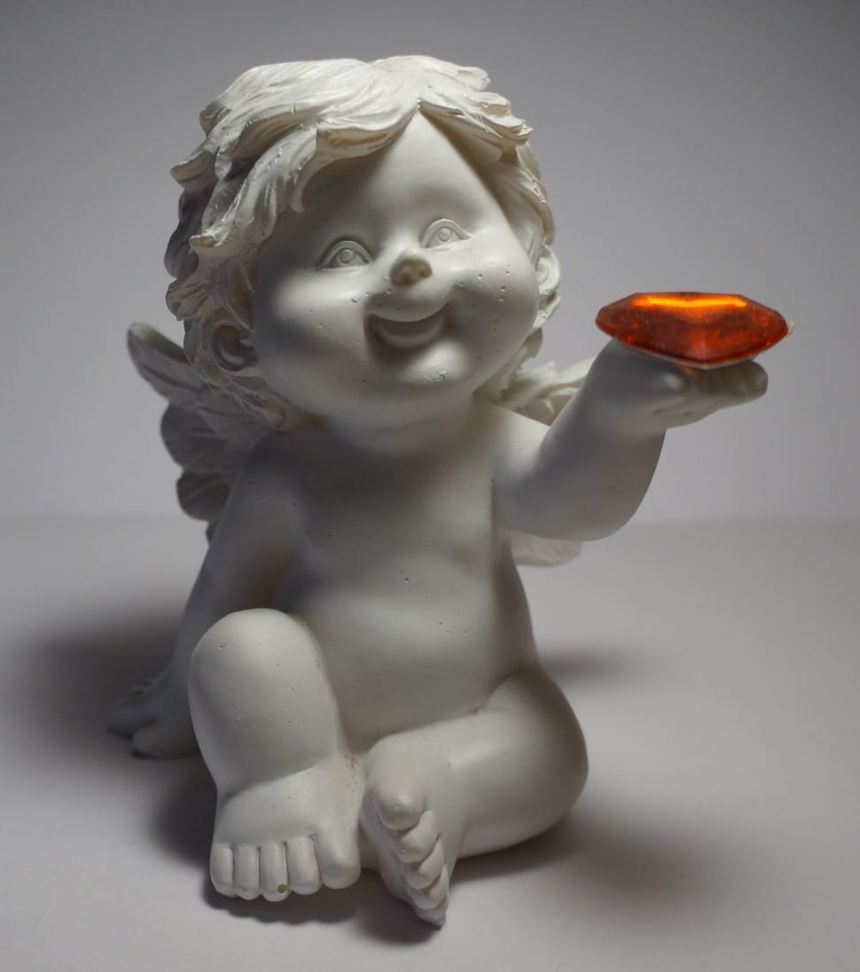 white cherub holding brown gemstone figurine preview