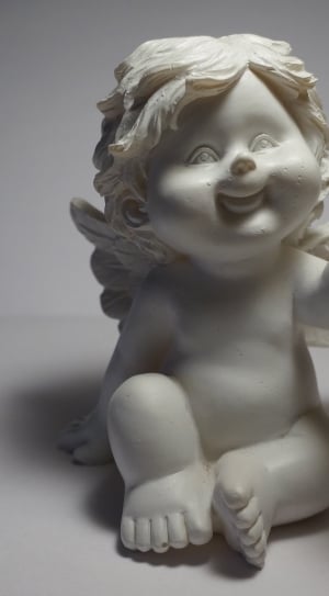 white cherub holding brown gemstone figurine thumbnail