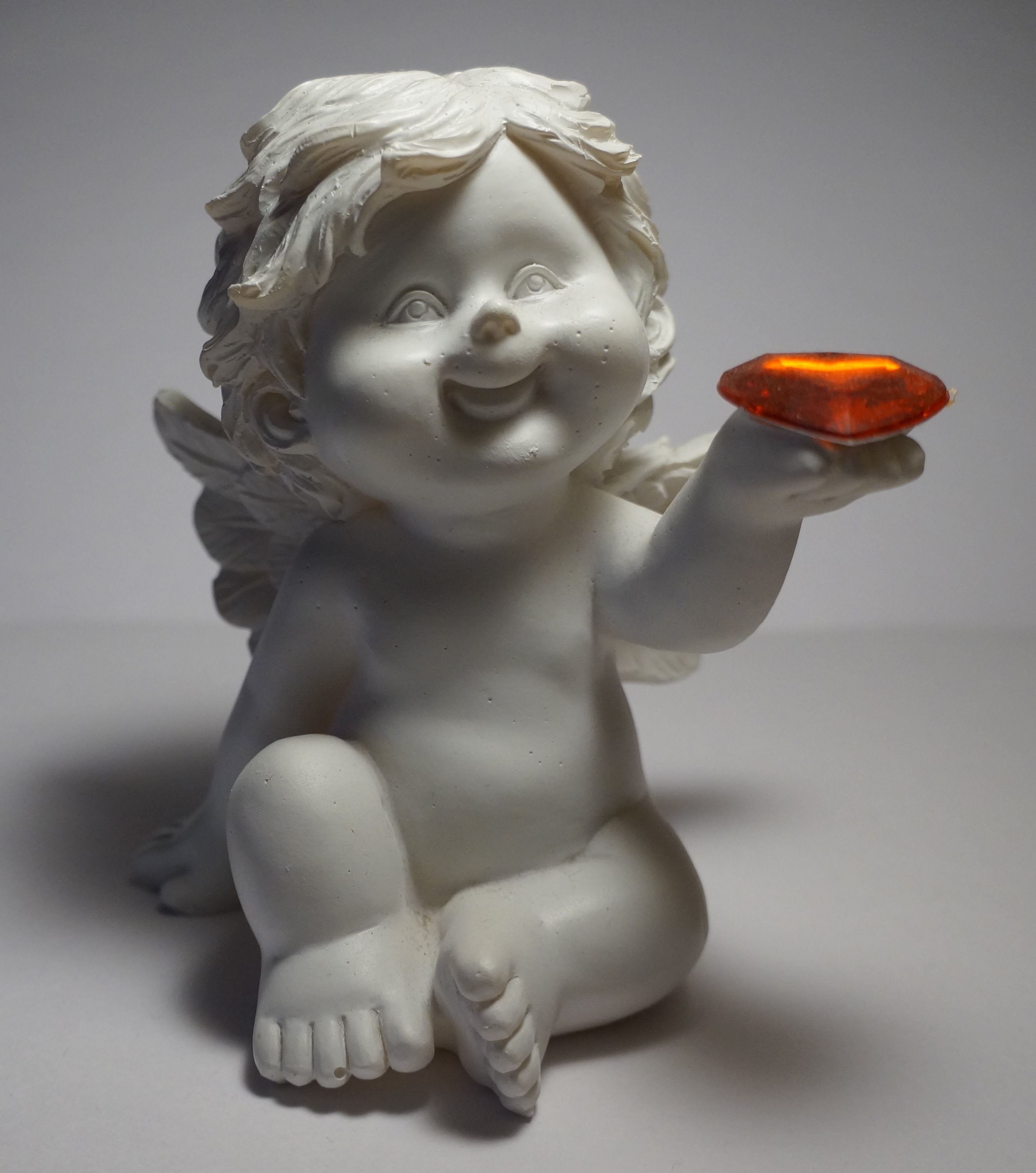 white cherub holding brown gemstone figurine
