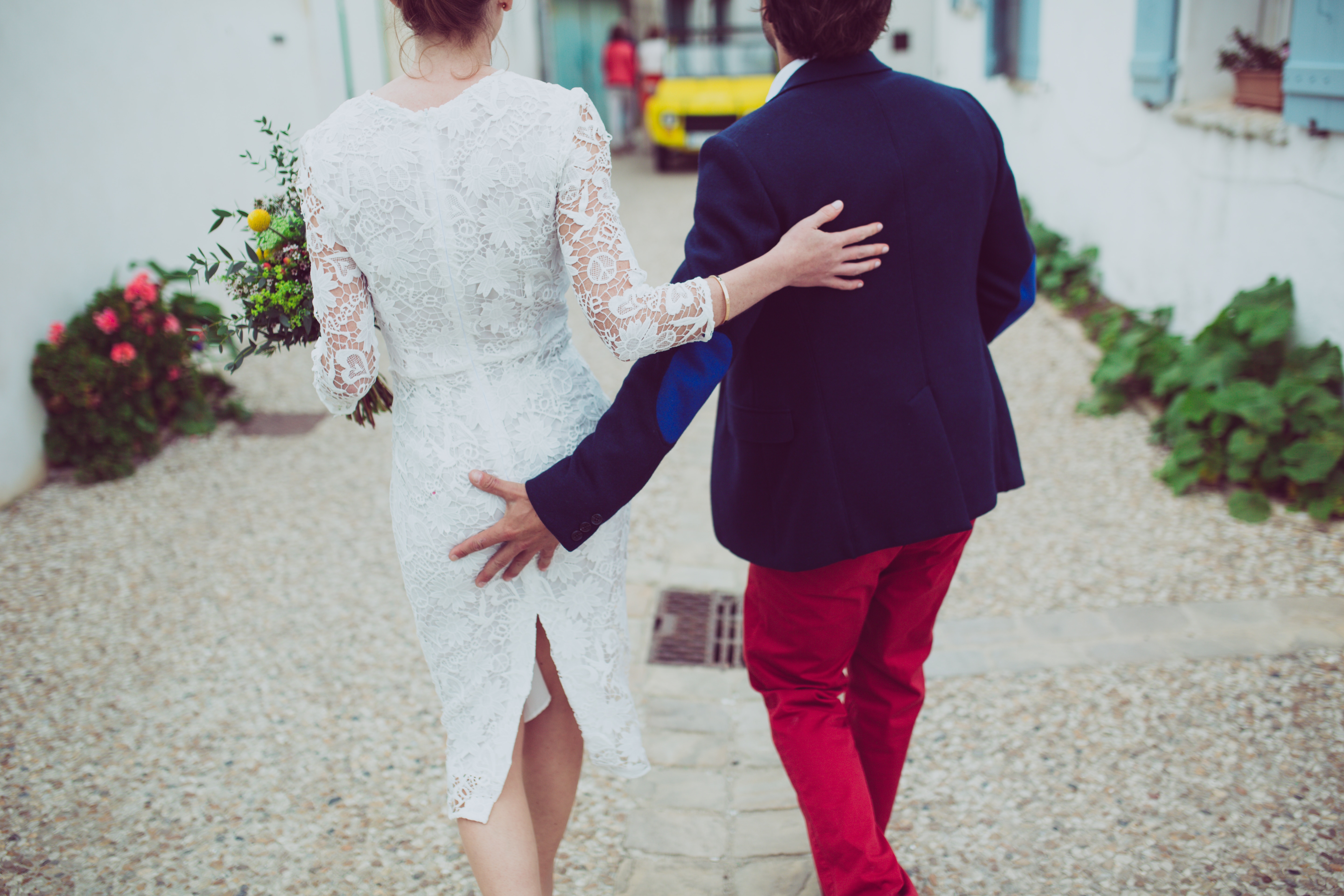 man in blue formal suit jacket and red pants outfit beside woman in white floral long sleeve outfit during daytime