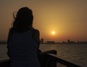 silhouette of waman near ocean during sunset photo thumbnail