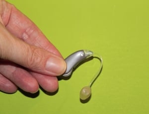 person holding gray earpiece thumbnail