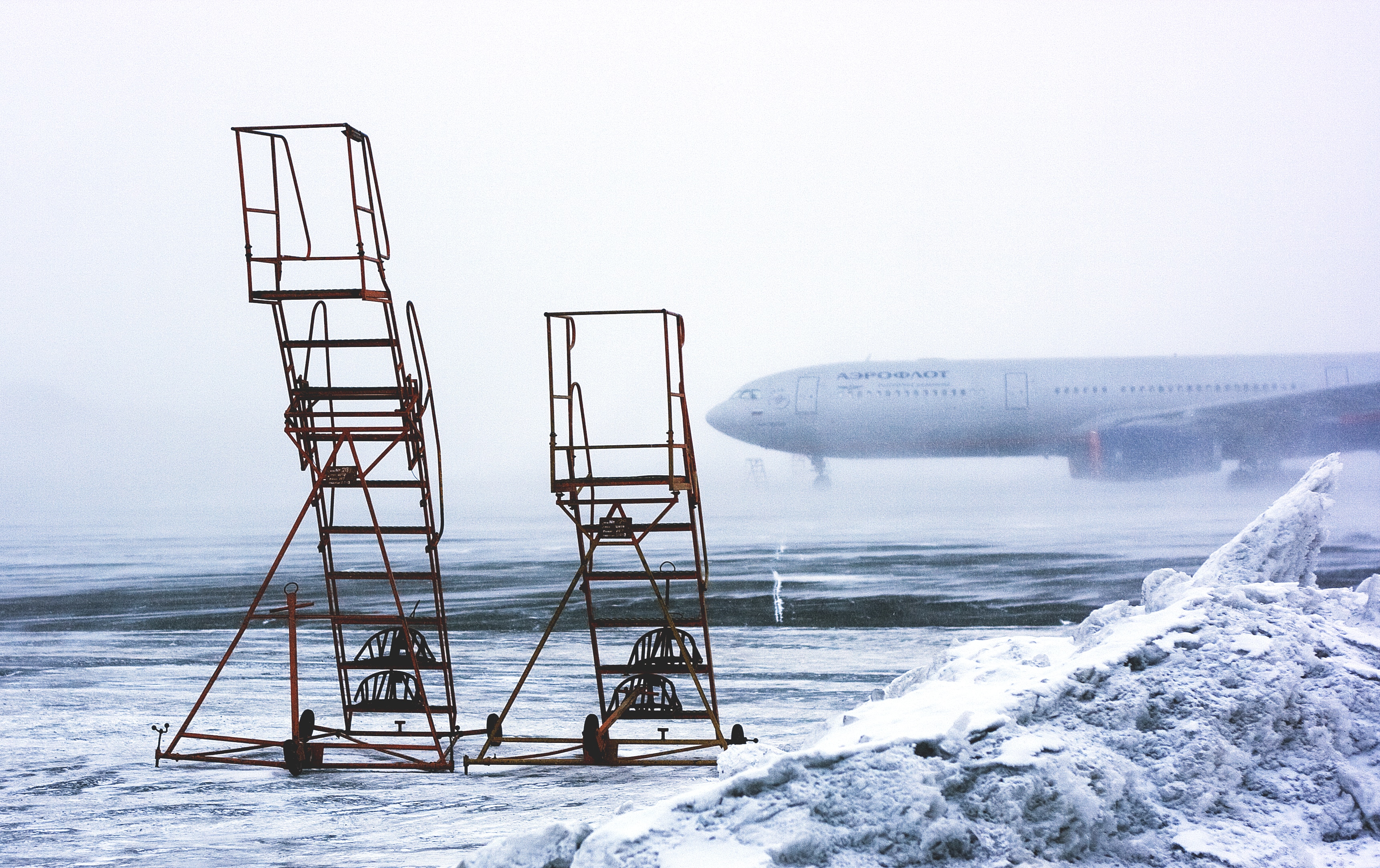 two brown steel wheeled airplane stairs on snow field during daytime