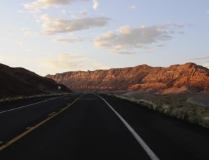 black road between rock formation mountain during daytime thumbnail