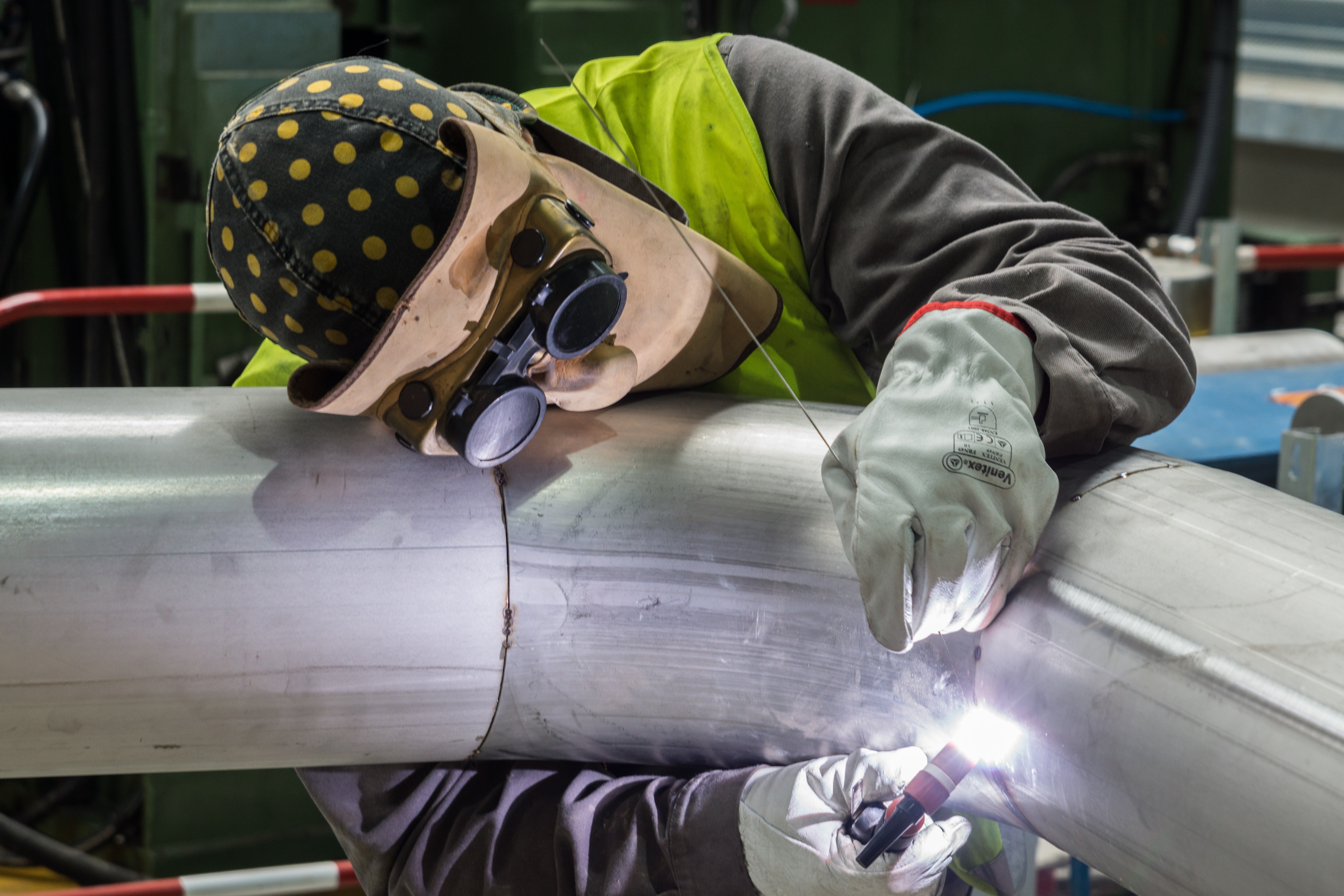 man welding gray metal pipe