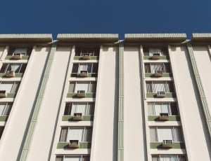 low angle photography of a white and green high rise building during a sunny weather thumbnail