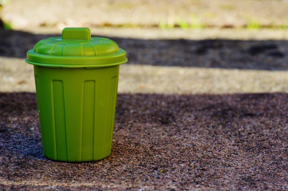 green plastic trash bin on brown soil preview