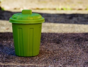 green plastic trash bin on brown soil thumbnail