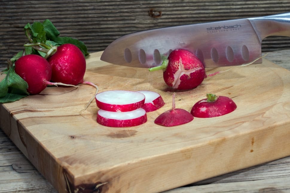 red fruit sliced on brown wooden cutting board with stainless steel kitchen knife preview