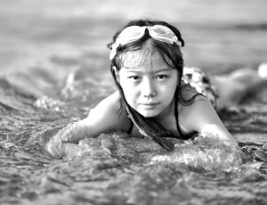 girl with swimming goggles laying on beach shore thumbnail