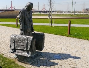 grey statue of man carrying two luggages thumbnail