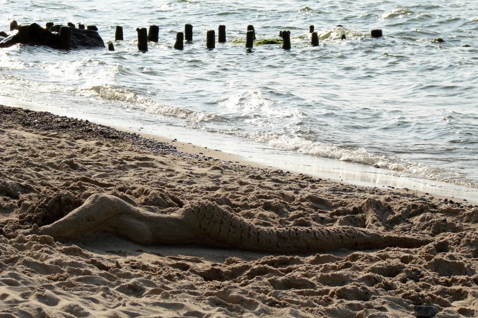 woman shape sand near body of water at daytime preview