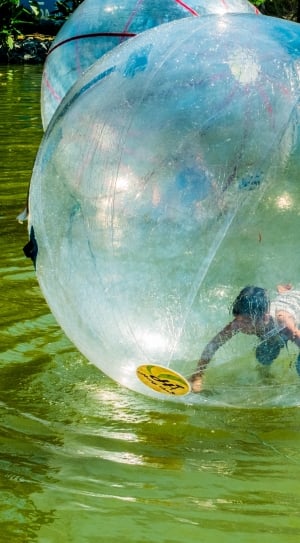 boy inside bubble on top of water photo during daytime thumbnail