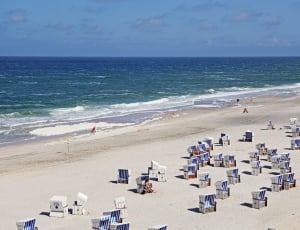 white and blue beach benches on white sand thumbnail