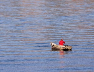 person on brown wooden boat in the middle of water thumbnail