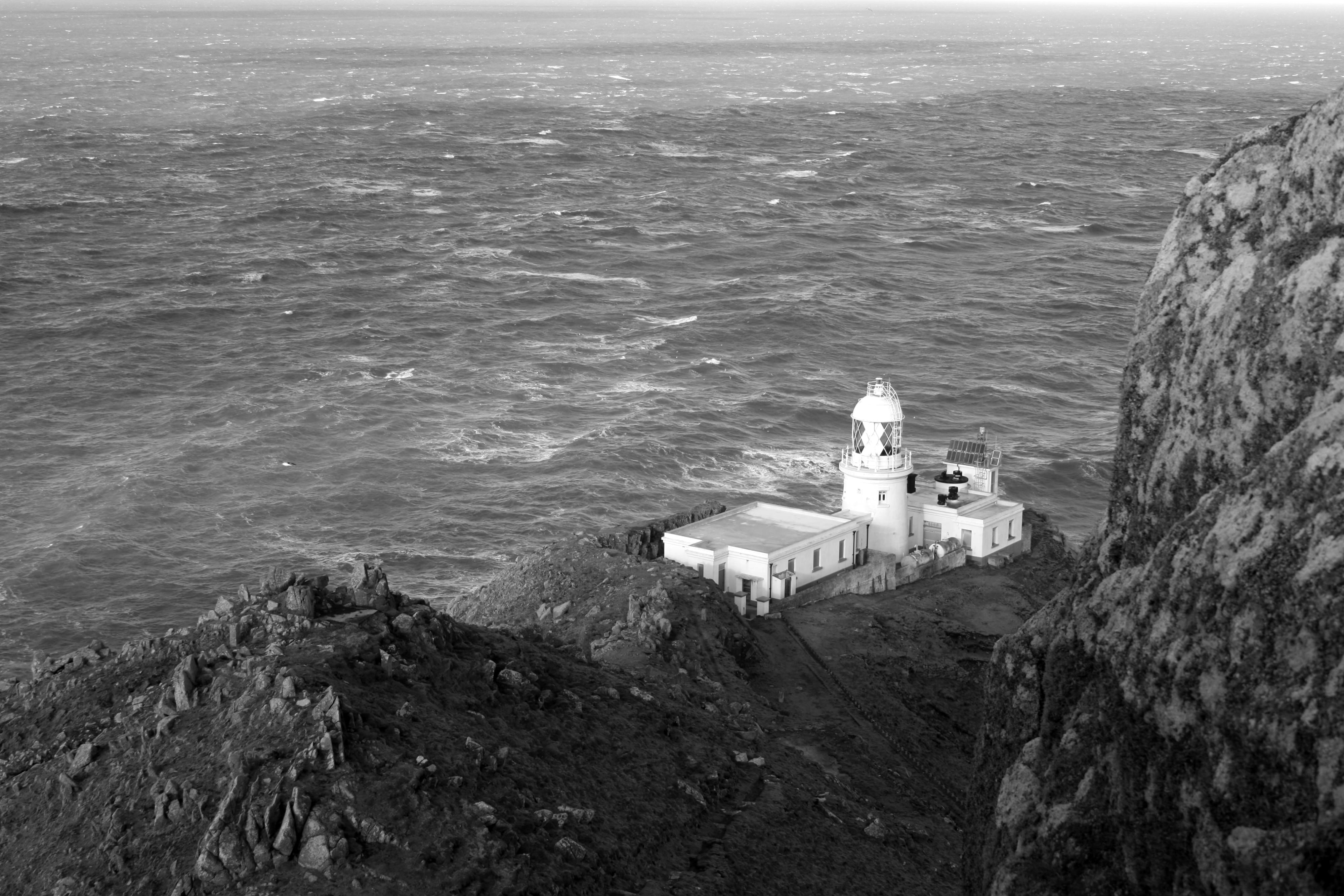 grayscale photography of lighthouse tower beside sea
