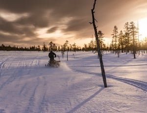 person riding snow mobile under black and brown sky thumbnail