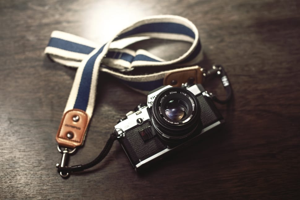 black mini camera with lanyard on top of wooden surface preview