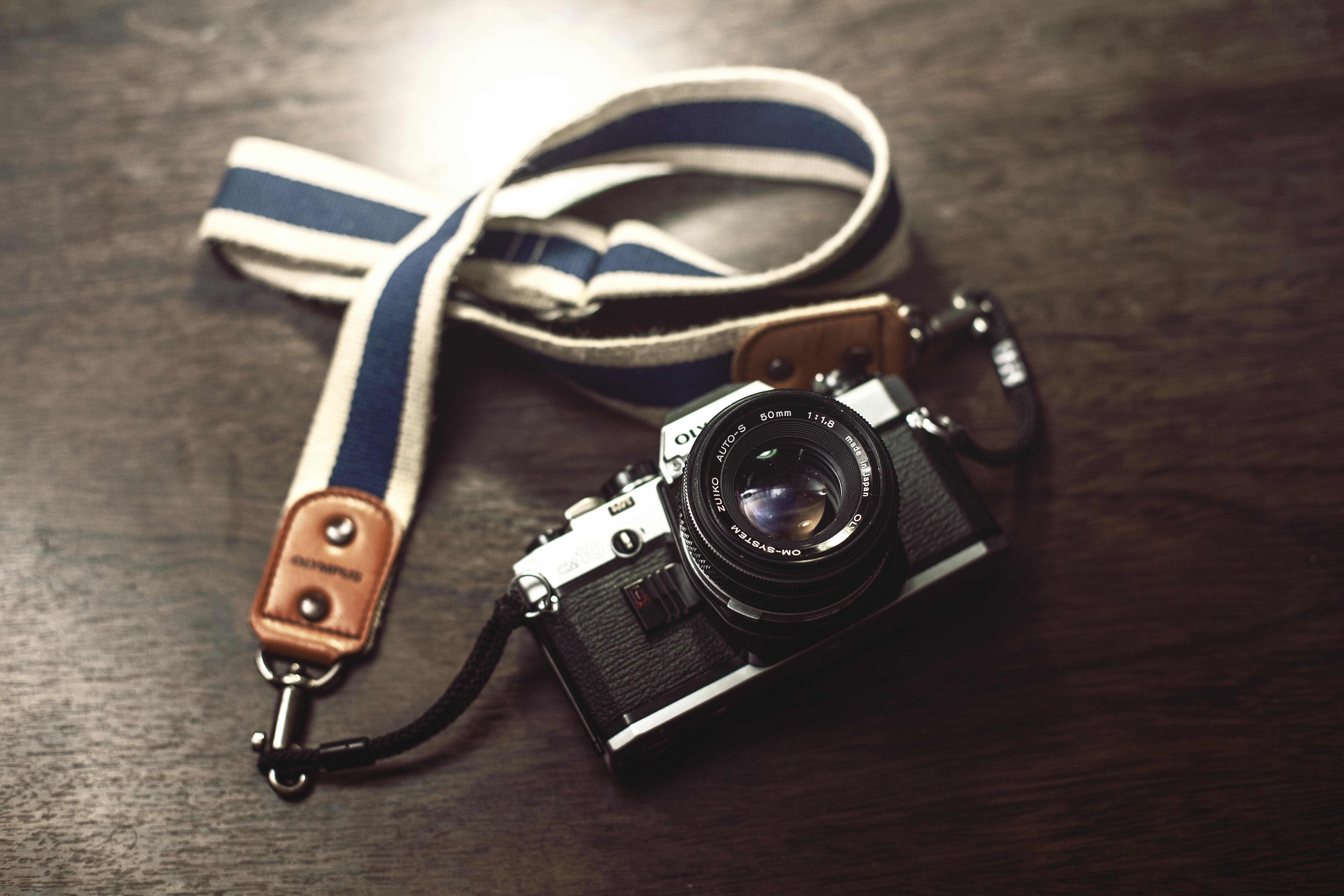 black mini camera with lanyard on top of wooden surface
