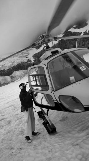 grayscale photography of man going in helicopter thumbnail