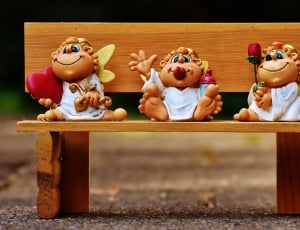 white and brown cherub sitting on bench figurines thumbnail