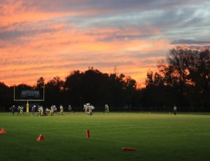 photography of football field with ongoing football game on sunsety thumbnail