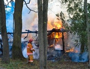 house on fire on a forested area with a fireman thumbnail