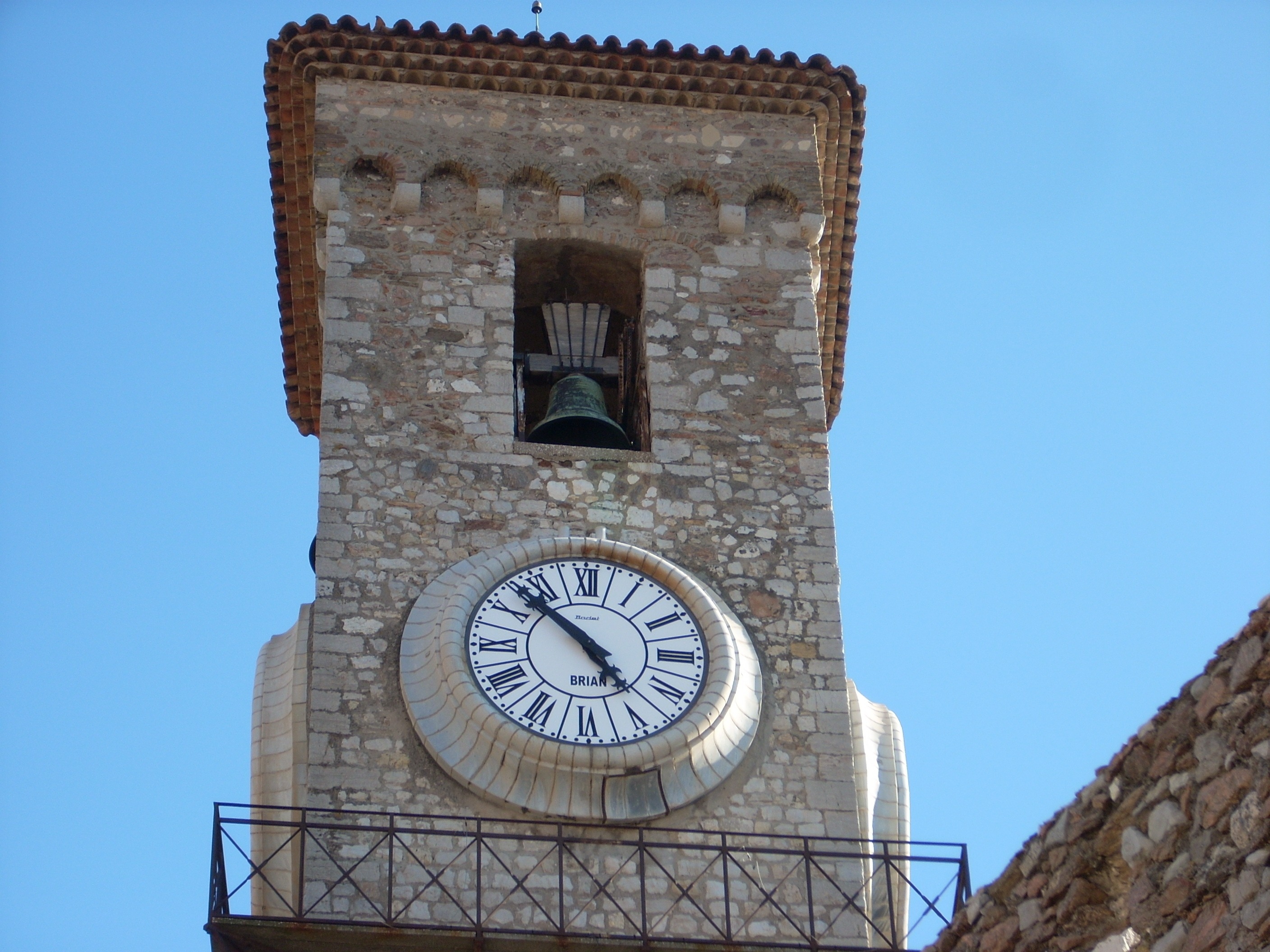 white analog clock mounted on concrete tower with bell on top