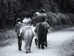 childrens riding on horses grayscale photo thumbnail