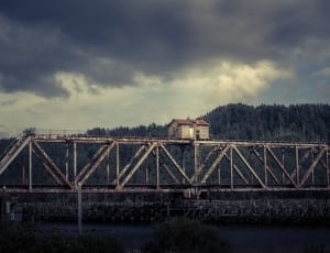 white and brown house on white steel bridge above river under grey sky thumbnail