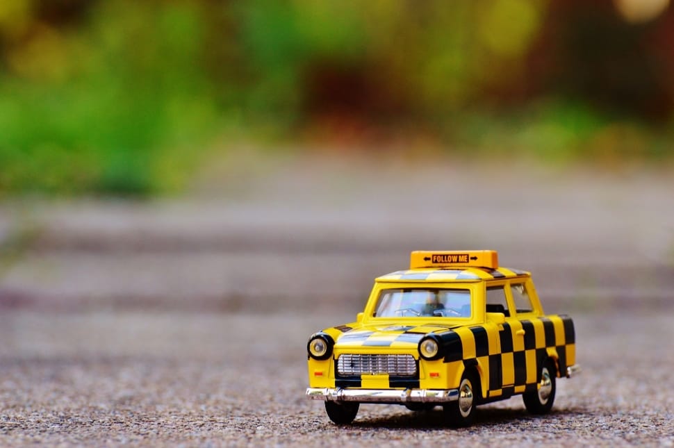yellow and black taxi car toy on floor preview