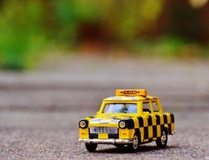 yellow and black taxi car toy on floor thumbnail