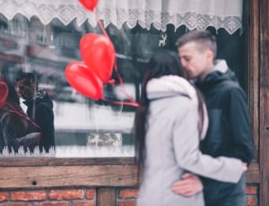 man in black hoodie kissing woman in grey hoodie in front of store thumbnail