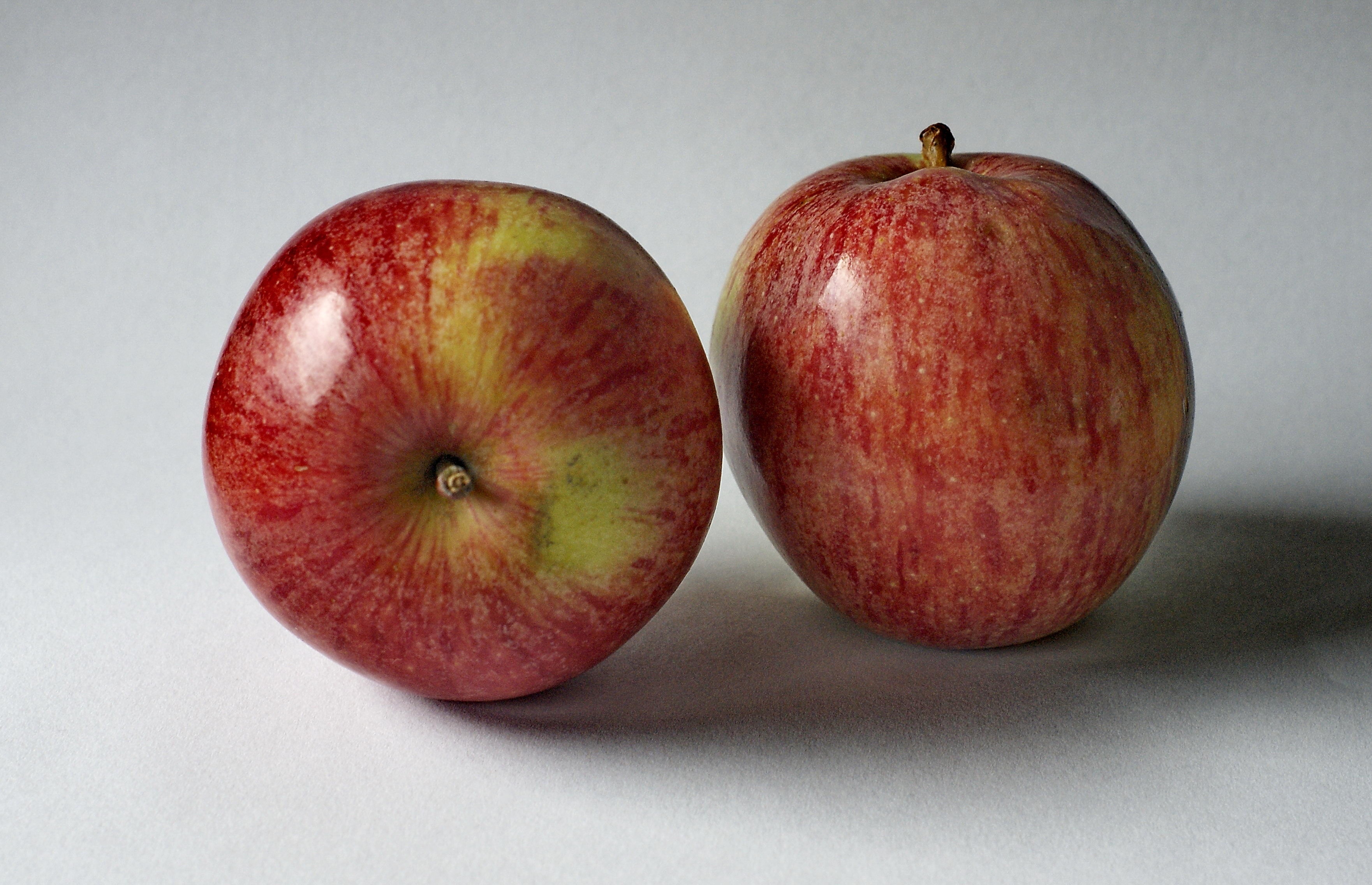 two red apples on white surface