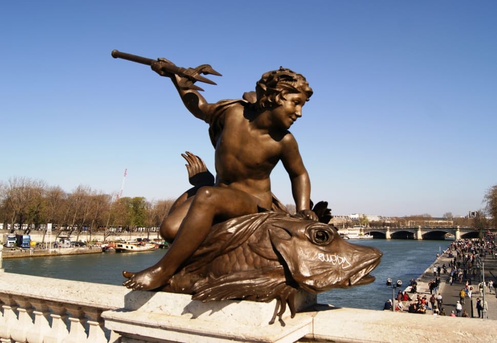 Staty av pojke som rider på en fisk med sin treudd