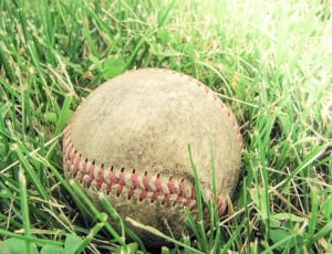 white and red baseball on green grass field thumbnail
