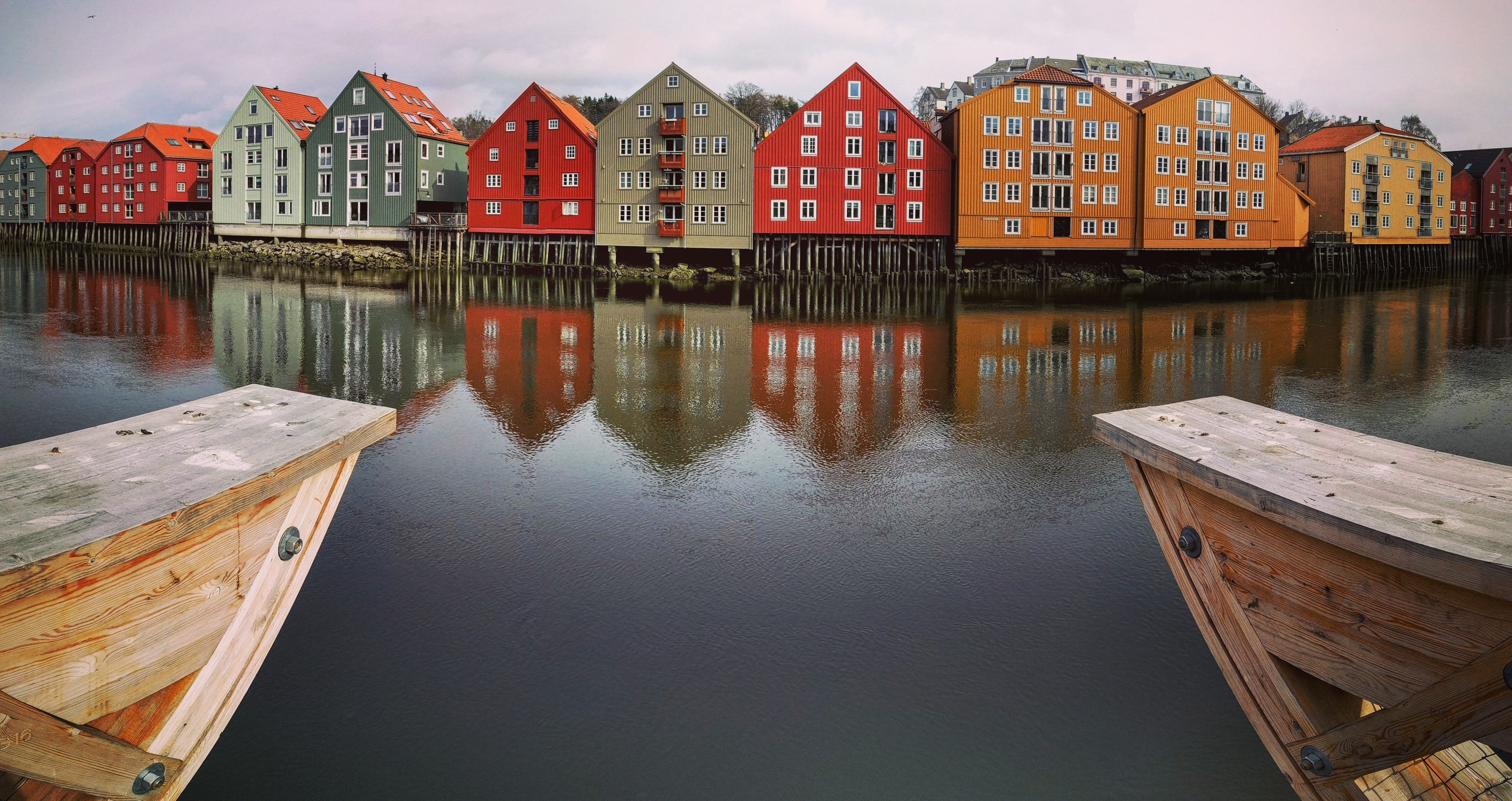 multicolored houses near lake under cloudy sky