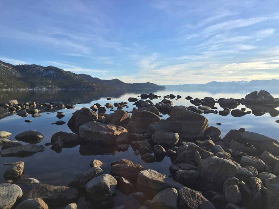 gray rocks on calm body of water during daytime preview
