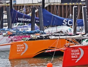 orange and red volvo ocean race boats dock on seaside thumbnail
