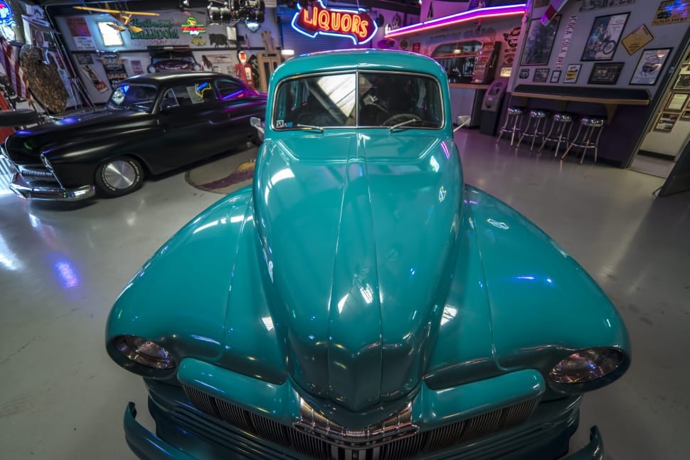 front of teal vintage car in showroom preview