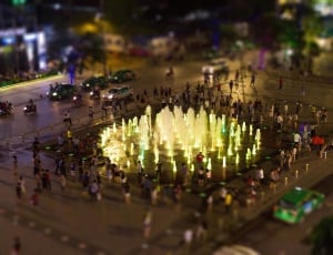 tilt photography of people beside fountain and cars at nigh time thumbnail