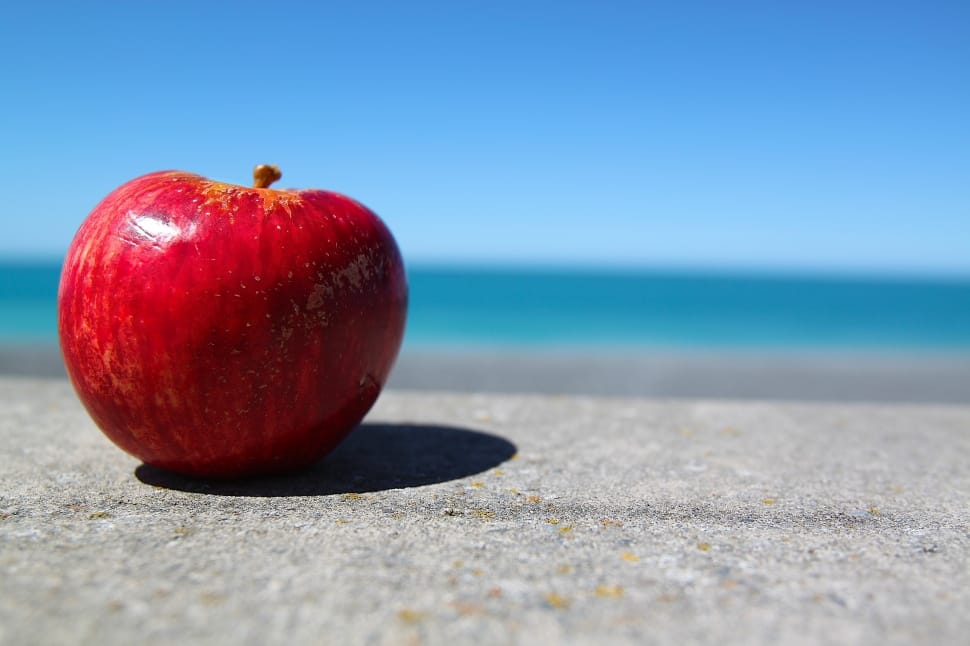 red apple fruit on gray sand under cloudy sky during daytime preview