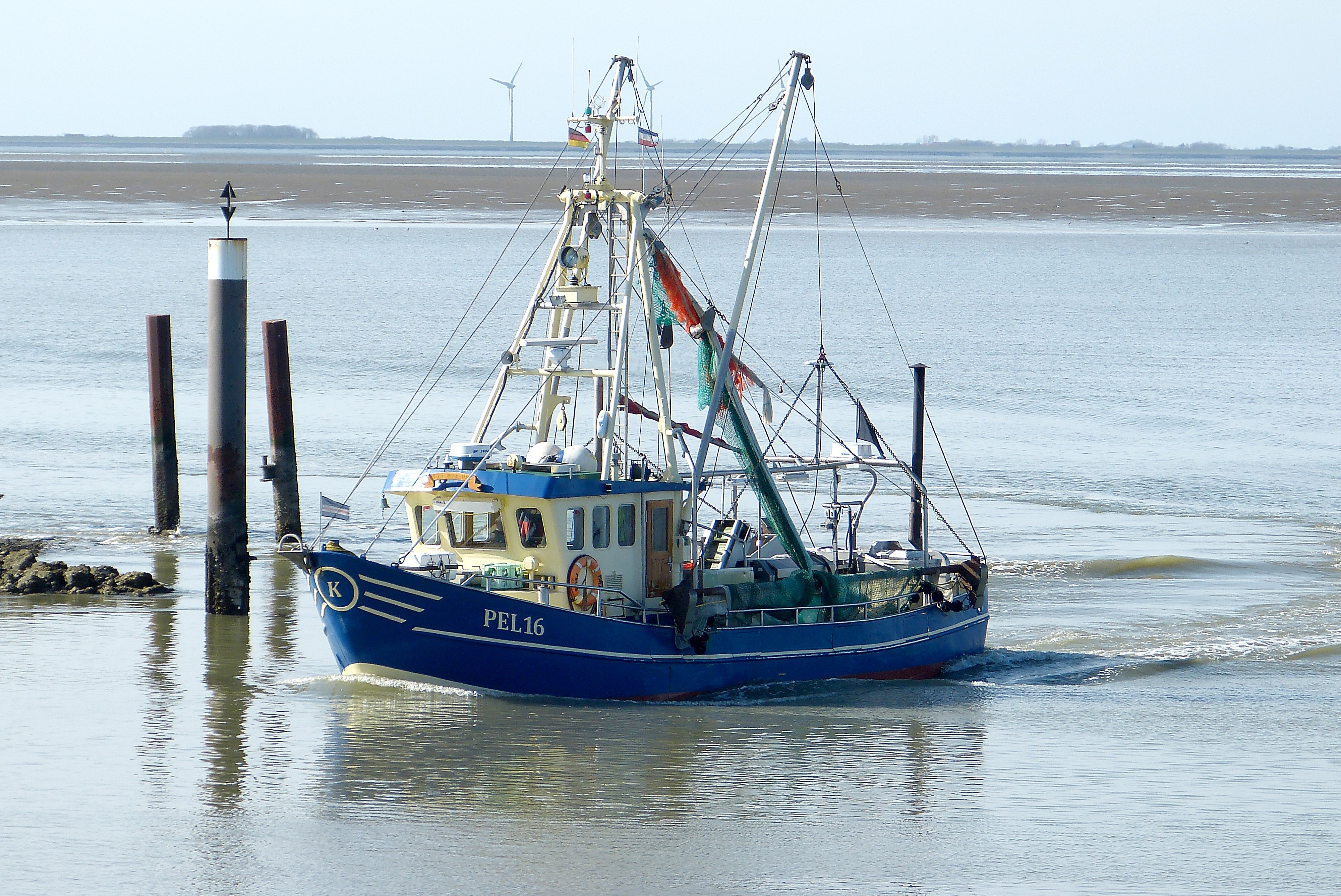 blue and white fishing boat on body of water near brown wooden post