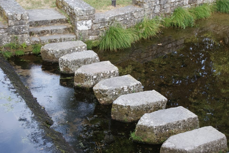 gray slab stepping stones on a body of water during day time preview