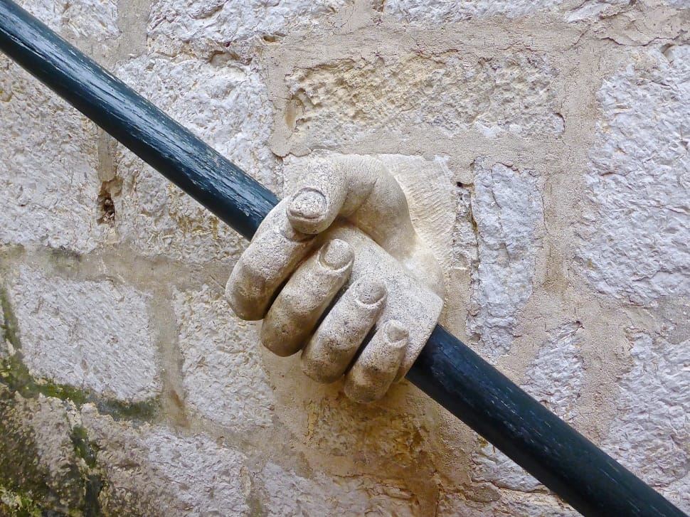beige concrete hand holding black metal pole preview